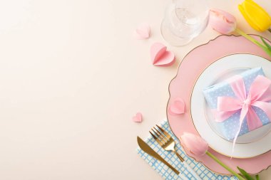 Kadınlar Günü masa dekorasyonu konsepti. Zarif tabak, çatal, bıçak, şarap kadehi, canlı laleler, yumuşak bej arka planda duran kalpler, mesaj ya da reklam için yer bırakırlar.
