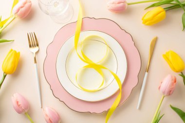 Kadınlar Günü yemek konsepti: 8 şekilli kurdele, çatal bıçak, şarap kadehi, yumuşak kremsi bej arka planda narin laleler ile müsrif bir tabağın yukarıdan çekimi