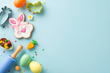 Şekerleme dükkanı Paskalya için hazırlanıyor. Pişirme aletleri olan masa manzarası. Sevimli tavşan kurabiyesi, şekerleme, açık mavi yüzeyde çikolatalı yumurta. Metin ya da reklam eklemek için mükemmel