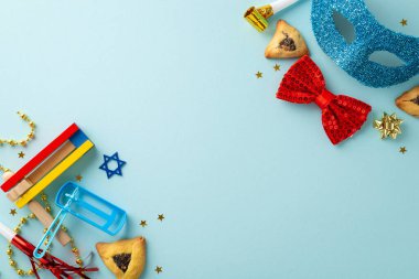 Purim theme top view photo: Triangle cookies, Star of David motifs, and celebration accessories such as bow tie, beads, and graggers on a baby blue backdrop, with a spot for text or ads clipart