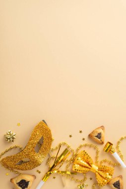Cömert Purim etkinliği için davetiye konsepti. Üçgen hamur işlerinin dikey fotoğrafı ve bej tuval üzerinde maske, hava üfleyici ve konfeti gibi varlıklı altın eşyalar.