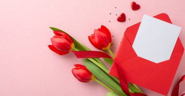 Romantik evlilik teklifi, aşk notları içeren bir zarf, dağınık pullar, kalp şekilleri ve yumuşak pembe arka planda kurdeleyle bağlanmış taze lalelerden oluşan bir buket.