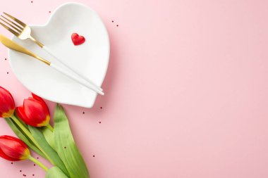 Büyüleyici 8 Mart kutlama seti. Akşam yemeği sahnesinin resmi, kalp şeklinde tabak, özel çatal bıçak seti, pullar, aşk sembolleri, pembe arka planda bir buket lale.