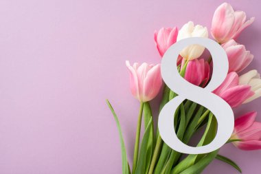 Kadınlar Günü üst görünüm kompozisyonu: Bir buket lale tarafından çerçevelenmiş, açık mor arka planda konumlandırılmış, kişiselleştirilmiş metin için geniş bir alan sunan 8 numara
