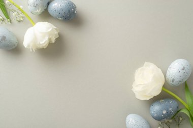 Paskalya sükuneti: Sofistike dumanlı yumurtaların üst görünümü, ince çingene, beyaz laleler, açık gri bir arkaplana ustaca yerleştirilmiş, mesaj için boşluk bırakarak