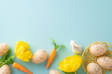 Renkli Paskalya düzenlemesi. Üst manzara yumurtaları bir kâseye, havuçlara ve lalelere yerleştirilmiş. Sanatsal olarak mavi bir tuval üzerine yerleştirilmiş.