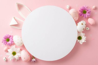 Sofistike Paskalya konsepti çekimi. Yumurtaların üst görüntüsü, çiçek açan kasımpatılar ve yumuşak pembe arka planda konfeti. Tavşan kulakları, mesaj ya da reklam için boş bir ana hatdan gizlice bakıyor.