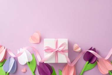 Annem için bir kutlama. Origami lalelerinin üst perspektifi, kurdeleli bir kutu, ve yumuşak mor bir tuvaldeki küçük kalpler, kişisel mesajlar için yer sunuyor.