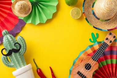 Cinco de Mayo şenlikleri. Üst düzey fotoğraf gösterisi parti esasları, minyon sombrerolar, dekoratif vihuela, hayranlar, bıyıklı bir kaktüs, baharatlı biber ve sarı arka planda limon.