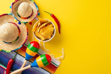 Cinco de Mayo tuzağı. İkonik öğelerin üst görüntüsü: küçük sombrerolar, bir marakalar, çizgili bir serape, acı biberler, ve sarı bir tuvale yerleştirilmiş nachos.