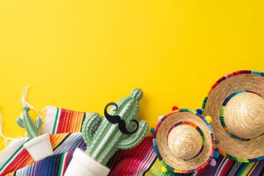 Cinco de Mayo koleksiyonu. Sembolik parçaların genel görünümü: küçük sombrerolar, dekore edilmiş bir kaktüs, güneşli sarı bir arka planda dizilmiş desenli bir serape.