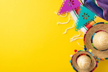 Cinco de Mayo teması. Tepede şenlik öğeleri yer alıyor: mini sombrerolar, renkli serape, canlı sarı bir zemin üzerinde bayraklar dizisi, metin için boşluk