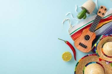 Geleneksel sembollerin üst görüntüsüyle Cinco de Mayo 'yu kutlayın: sombreros, bir vihuela, tencere içinde kaktüs, çizgili bir serape, acı biber ve açık mavi arkaplan üzerinde limon, mesaj için boşluk