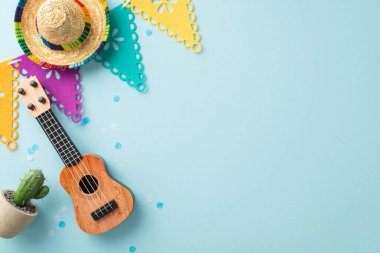 Cinco de Mayo simgelerinin üst görüntüsünden ekran görüntüsü: şapka, vihuela, saksı kaktüsü, bayraklar çelenk, soluk mavi bir yüzeyde konfeti, metin veya reklamlar için uygun alan