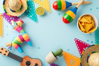 Cinco de Mayo sembollerinin tepeden ele geçirilmesi: Sombreros, vihuela, maracas, kaktüs, canlı bir pinata, bayraklar ve nachos, açık mavi bir arkaplanda, mesajınız veya reklamınız için yer var.