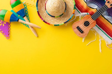 Cinco de Mayo için şenlik düzeneği. Üst görünümde geleneksel dekor sergileniyor: şapka, gitar, marakas, çizgili battaniye, flamalı bayraklar, sarı üzerine servis edilen, kopyalamak için boş alan