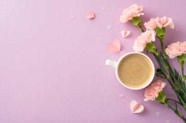 Bahar dönemi şık estetiği: Taze kapuçino, karanfiller, küçük kalpler ve konfetilerin üst görünüm görüntüsü, yumuşak bir leylak arkaplan üzerine yayılmış, kelimeler ve reklamlar için boş bir alan.