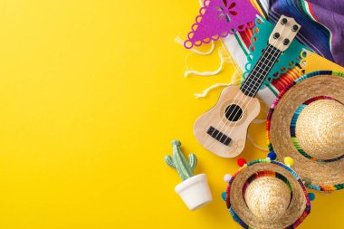 Cinco de Mayo 'yu kutluyoruz. Geleneksel şapkalar, küçük bir vihuela, tencerede kaktüs, çizgili serape ve parlak sarı bir yüzey üzerindeki dekoratif bayraklar da dahil olmak üzere kutlama malzemelerinin en üst görüntüsü.