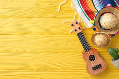 Cinco de Mayo dekoru: Sombreros, gitar ve kaktüs manzarası. Sarı ahşap bir masada renkli bir serape. Metin yerleştirme için ideal