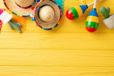 Sombreros, maracas ve kaktüs ile Bright Cinco de Mayo üst görünüm düzenlemesi. Sarı ahşap bir masanın üzerinde bayrak çelengi. Metin için uygun alan