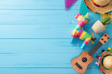 Cinco de Mayo titreşimlerini kucaklayın: Sombreros, vihuela, lama pinata, kaktüs, bayrak çelengi, ahşap mavi yüzeyde konfeti. Şenlikli mesajlaşma için ideal