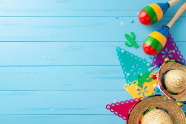 Şenlikli Cinco de Mayo kompozisyonu. Sembolik eşyalar: sombrerolar, marakalar, bayrak çelenkleri ve kırsal mavi yüzeyde konfeti. Etkinlik tanıtımları için uygun