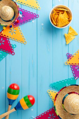 Vibrant Cinco de Mayo sombreros ve maracas ile dikey görüntü. Parlak bayrak çelengi ve mavi ahşap masada baharatlı nacho. Metin için uygun alan