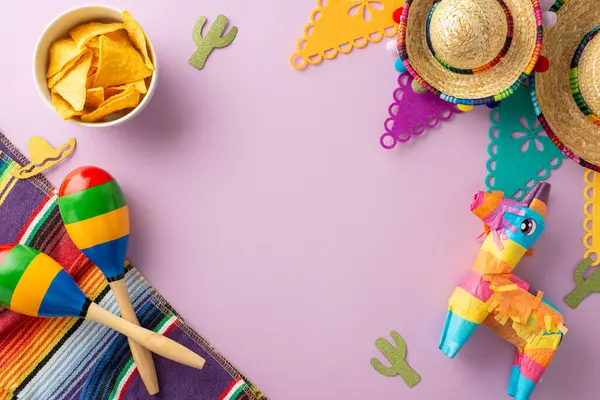 Kutlama Cinco de Mayo çerçevesi. Şenlikli aksesuarları vurgulayan genel resim: sombrero, lama pinata, marakas, renkli serape, bayrak iplikleri, bir kase nachos, lavanta arkaplan, metin için alan