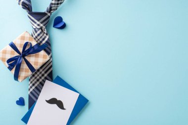 Babalar Günü 'nü göz kamaştırıcı üst düzey bir düzenleme, gösterişli bir kravat, fiyonklu bir hediye kutusu, bıyıklı bir kartpostal, dingin mavi arka planda kalpler, mesajlar ve reklamlar için ideal bir ortam.