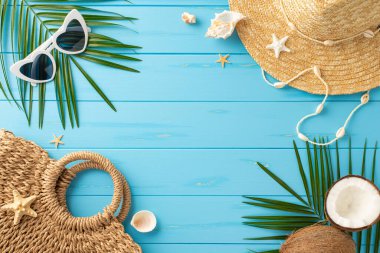 Mavi ahşap bir yüzey üzerinde hasır şapka, güneş gözlüğü ve tropikal elementler de dahil olmak üzere canlı ve davetkar bir yaz tatili eşyası yatağı.