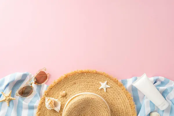 stock image Top view of a straw hat, stylish sunglasses, starfish, and sunscreen, neatly laid out on a striped cloth against a soft pink background. Perfect depiction of beach vacation and summer holidays