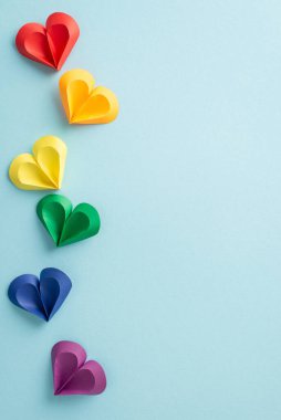 Çok renkli kağıt kalplerin çeşitli tonlarda dikey düzenlenmesi Gurur Ayı kutlamalarında çeşitliliği ve aşkı sembolize eder.