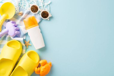 Sarı sandaletler, güneş gözlüğü ve parlak mavi bir arka planda güneş kremi gibi yaz plajı esaslarının düzenlenmesi.