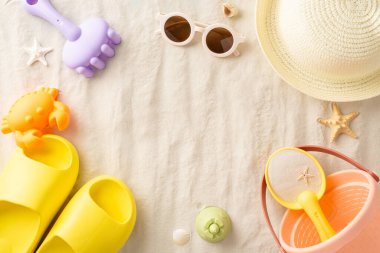 Çocuklar için yaz tatili. Plaj oyuncakları: kova, kürek, okyanus şekilli kalıplar, hasır şapka, güneş gözlükleri, küçük parmak arası terlikler, kum, deniz kabukları, kumlu zemindeki deniz yıldızları, reklamlar için mükemmel