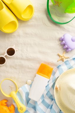 Deniz kenarında çocukların güneş güvenliğinden sorumlu. Güneş kreminin dikey üst görüntüsü, plaj oyuncakları, şapka, gölgeler, ve kumlu yüzeyde deniz kabukları ve reklam için ayrılmış küçük sandaletler.