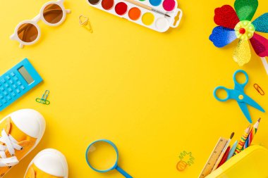 Çeşitli okul malzemelerinin neşeli ve parlak bir kompozisyonu parlak sarı bir arka planda serilmiş, eğitimin neşeli tarafını işaret ediyor.