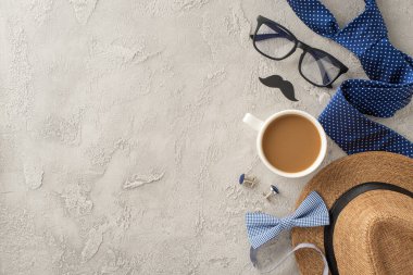 Babalar Günü için düz bir kompozisyon. İçinde bir kahve fincanı, bardaklar, şık bir şapka ve desenli beton arka planda aksesuarlar var.