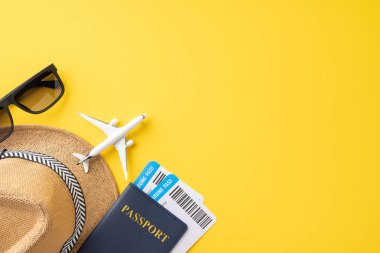 Yaz yolculuğunun temel unsurlarından biri olan şapka, pasaport, uçak modeli ve sarı arka planda güneş gözlüğü.