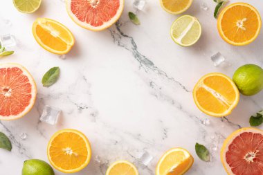 Buzlu taze narenciye meyveleri ve mermer arka plandaki nane yaprakları yaz atmosferini gösteriyor.