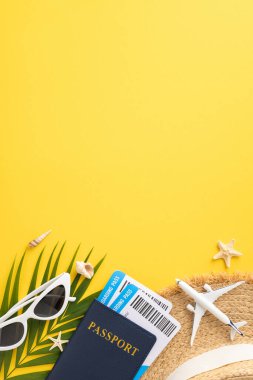 Pasaportlu yaz seyahati konsepti, uçuş kartları, güneş gözlükleri ve dikey sarı arka planda bir oyuncak uçak.