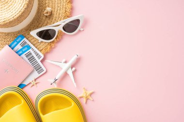 Yaz seyahatinin temel gereksinimleri. Şapka, güneş gözlüğü, biniş kartı, pasaport ve pembe arka plandaki uçak oyuncağı gibi.