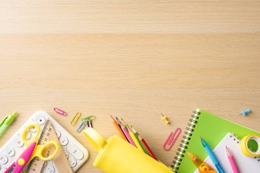 Ahşap masa arkasında çeşitli renkli okul malzemeleri, okul temalı resimlere ve eğitim içeriğine dönmek için ideal.