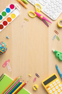 Çeşitli rengarenk okul malzemelerinin dikey üst görünüşü ahşap bir masanın üzerinde düzenlenmiş, okul temaları için mükemmel.