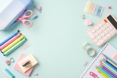 Kalemler, kalemler, hesap makinesi ve pastel arka planda düzenlenmiş ataç içeren canlı bir okul kırtasiyesi koleksiyonu.