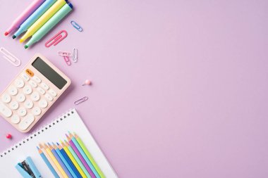 Renkli okul kırtasiyesinin üst görünümü pastel mor arka planda düzenlenmiş, kalemler, kalemler ve hesap makinesi sergileniyor.