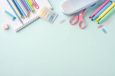 Renkli kırtasiye malzemeleriyle okul konseptine geri dönelim. Kalemler, keçeli kalemler ve ataçlar da dahil. Pastel mavisi arka planda.