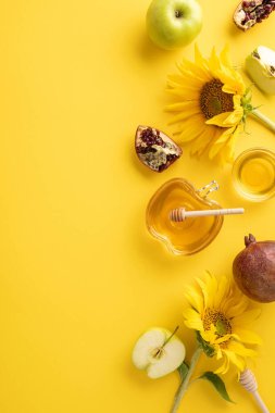 Canlı sarı dikey arkaplanda bal, elma, ayçiçeği ve nar içeren şenlikli Rosh Hashanah kompozisyonu