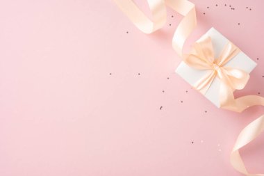 Pembe arka planda krem rengi bir kurdelesi olan zarif bir hediye kutusu. Doğum günleri, yıldönümleri ve düğünler gibi kutlamalar için mükemmel.