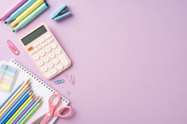 Okul teması için mor bir zemin üzerinde kalem, hesap makinesi ve defter içeren renkli okul sayfalarının üst görünümü