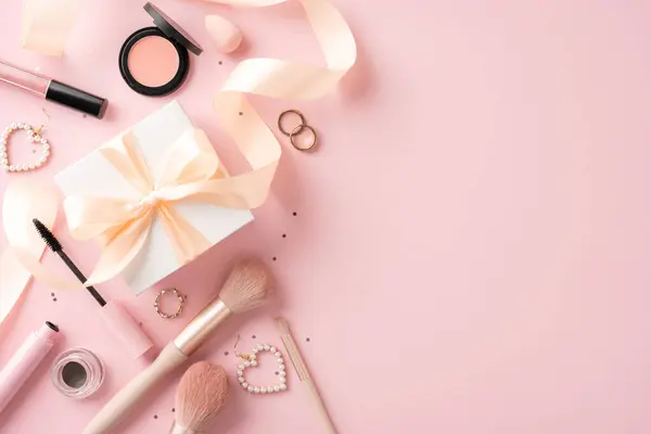 stock image Flat lay of various makeup tools and a gift box with ribbon on a pink background creating a feminine aesthetic